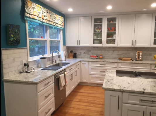 White kitchen with granite countertops, wood floors, and teal walls.