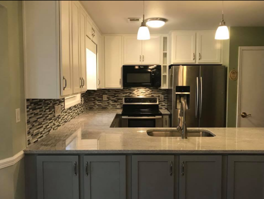 Modern kitchen with white and gray cabinets, stainless steel appliances, and gray countertops.