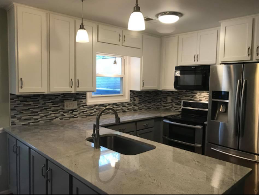 Kitchen with white cabinets, gray countertops, stainless steel appliances, and a mosaic backsplash.