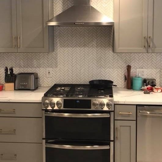 A modern kitchen with a stove, cabinets, and a range hood.
