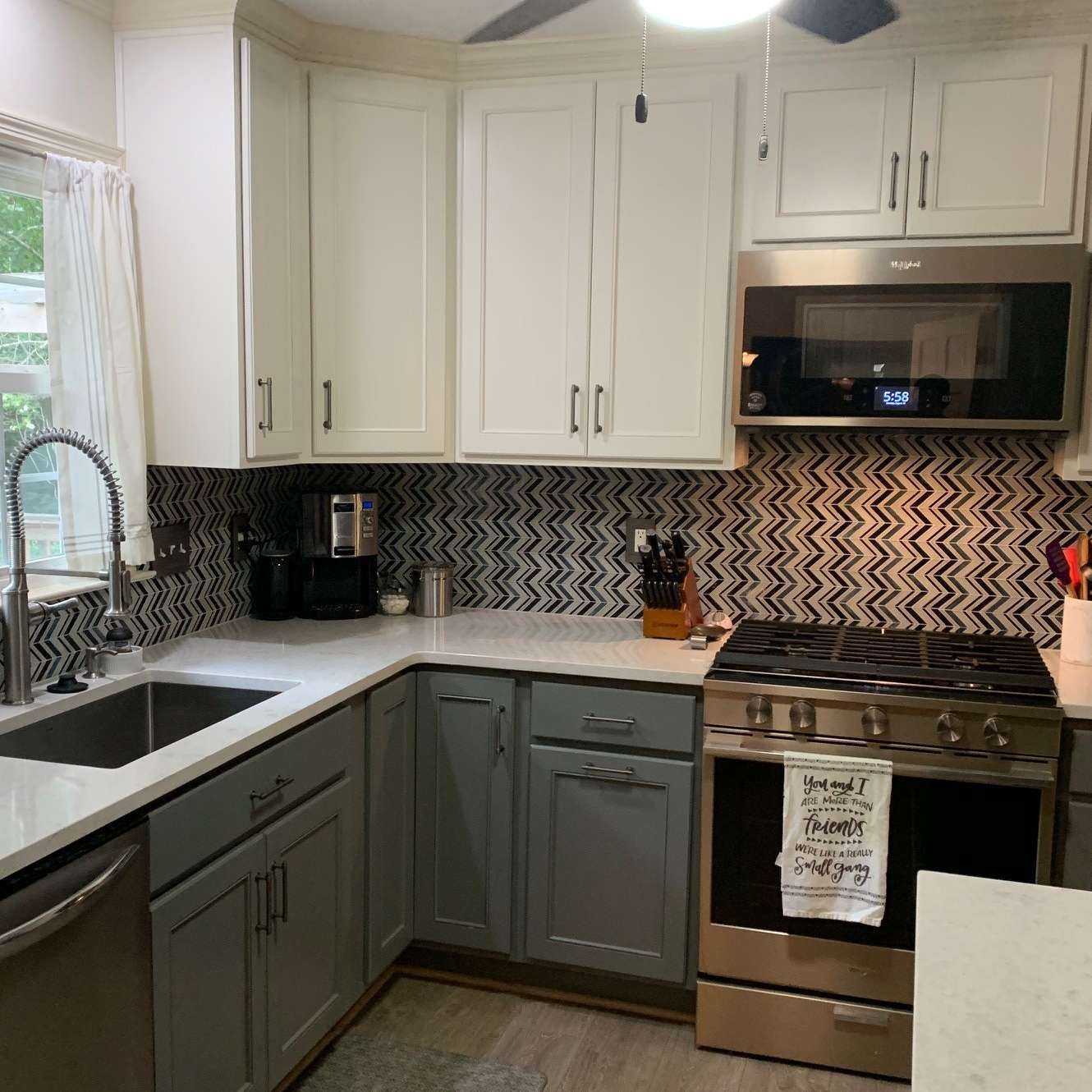 Kitchen with white and gray cabinets, stainless steel appliances, and chevron backsplash.