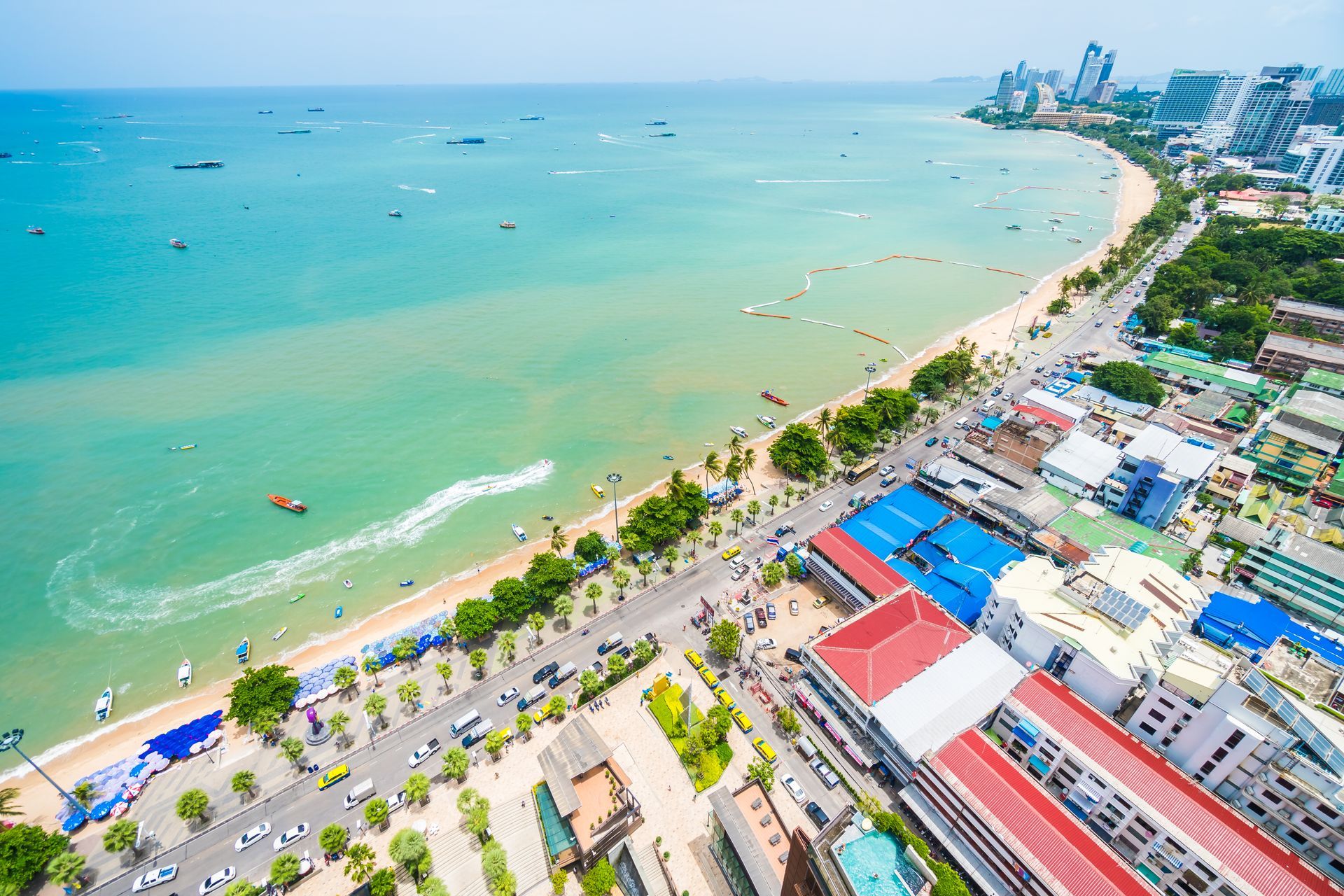 Aerial view of a coastal city with a beach, buildings, and turquoise water.