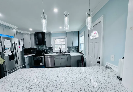 Kitchen with light blue walls, gray cabinets, stainless steel appliances, and a white countertop.