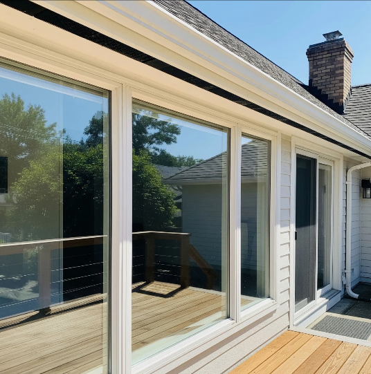 Exterior view of a house with large windows, a deck, and a brick chimney.