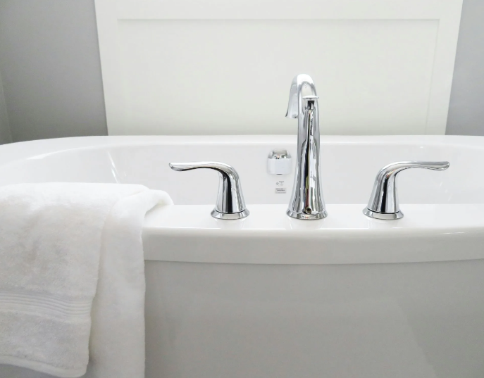 White bathtub with chrome fixtures, towel draped over the side.