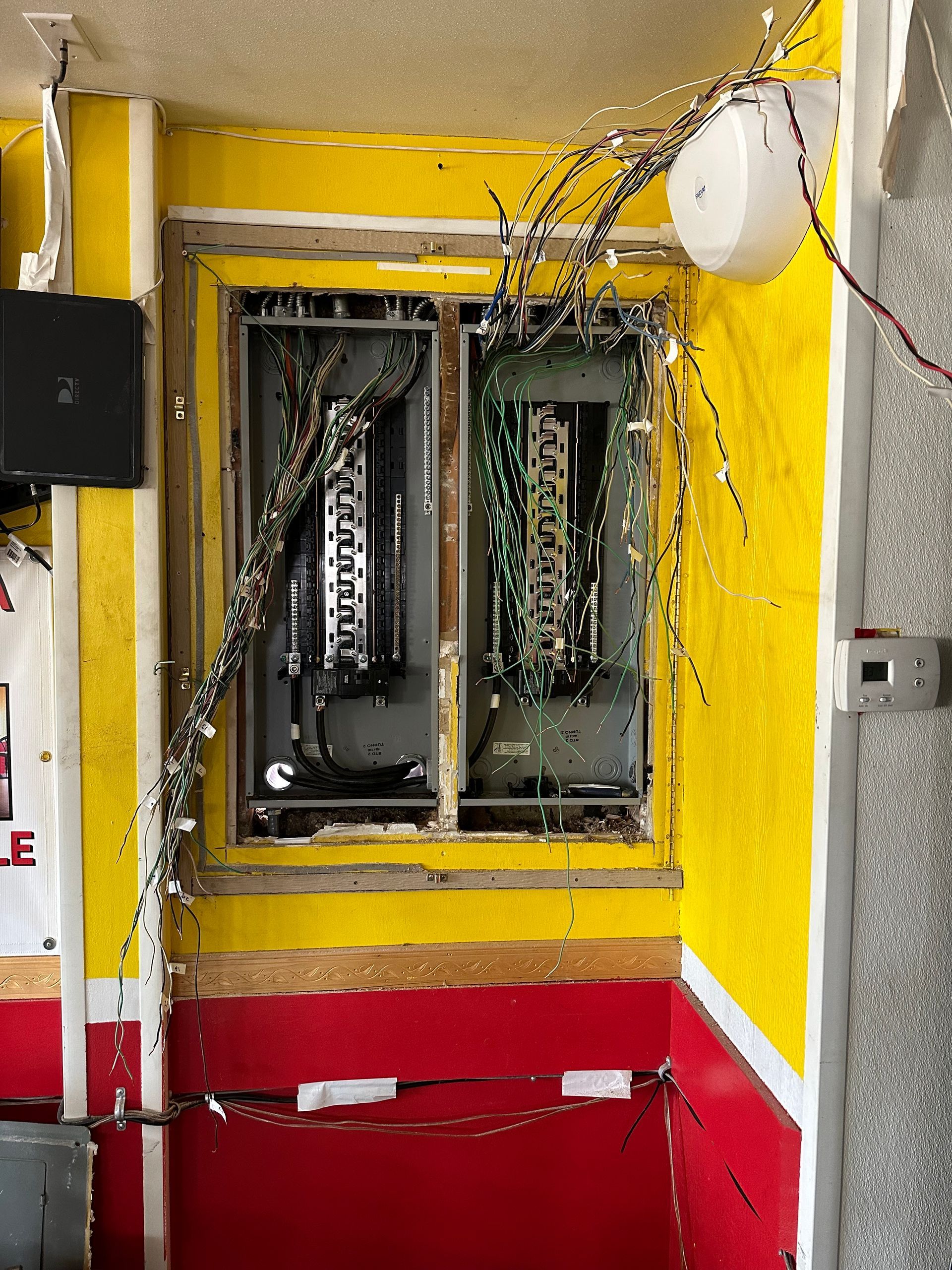 A yellow and red room with a broken window and a broken electrical box.