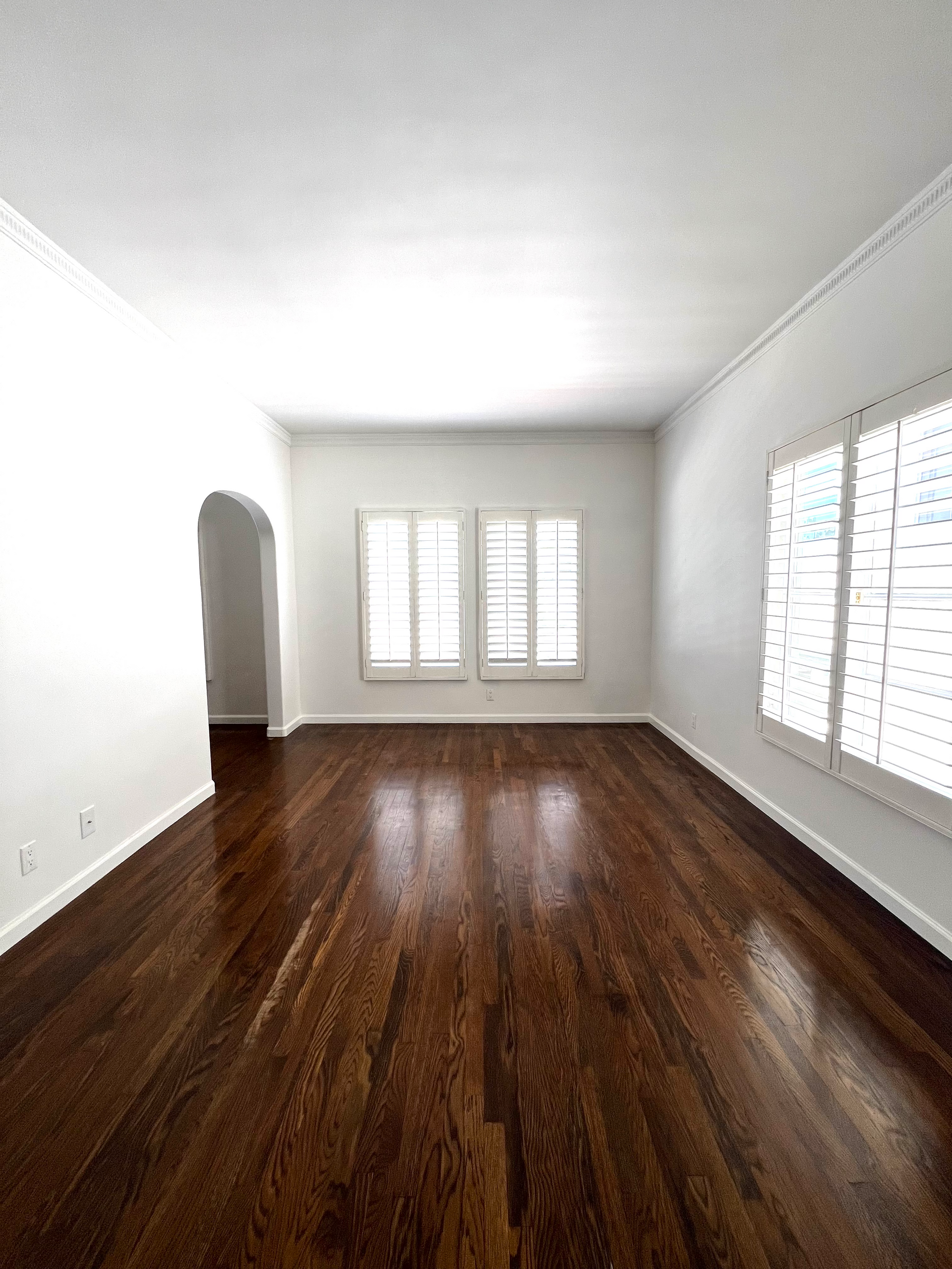 An empty living room with hardwood floors and white walls.