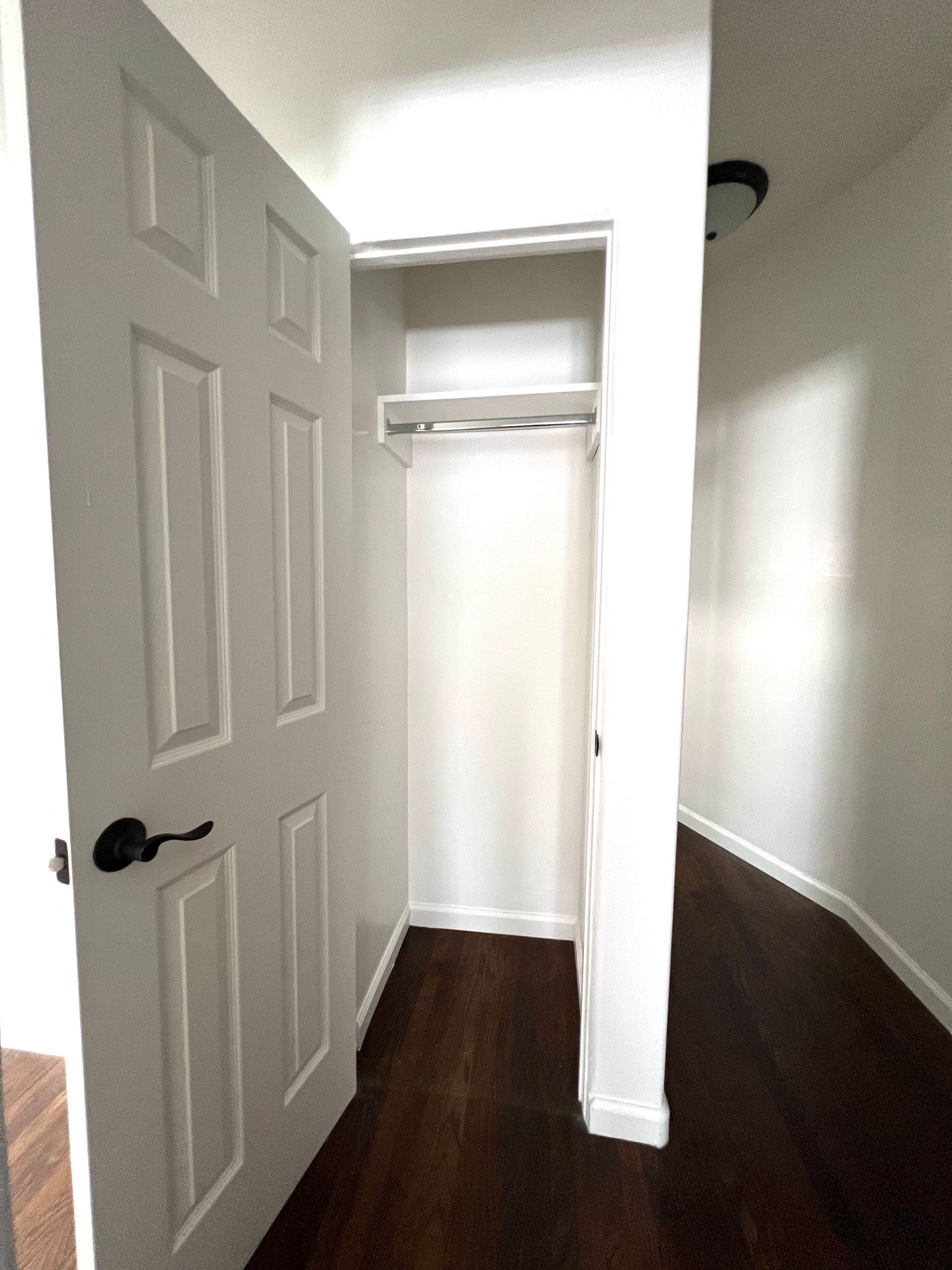 A closet with a door open and a shelf in it.