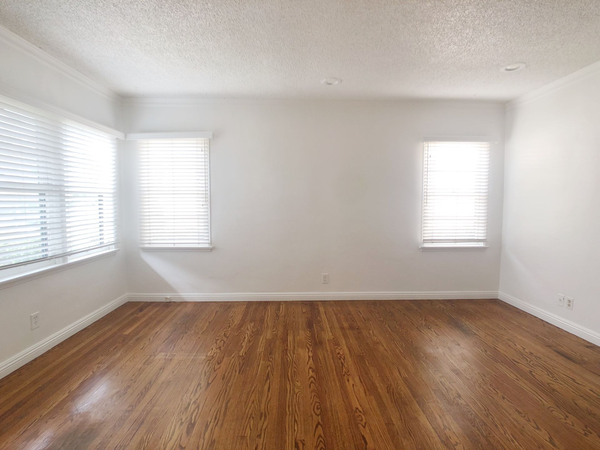 An empty room with hardwood floors and white walls