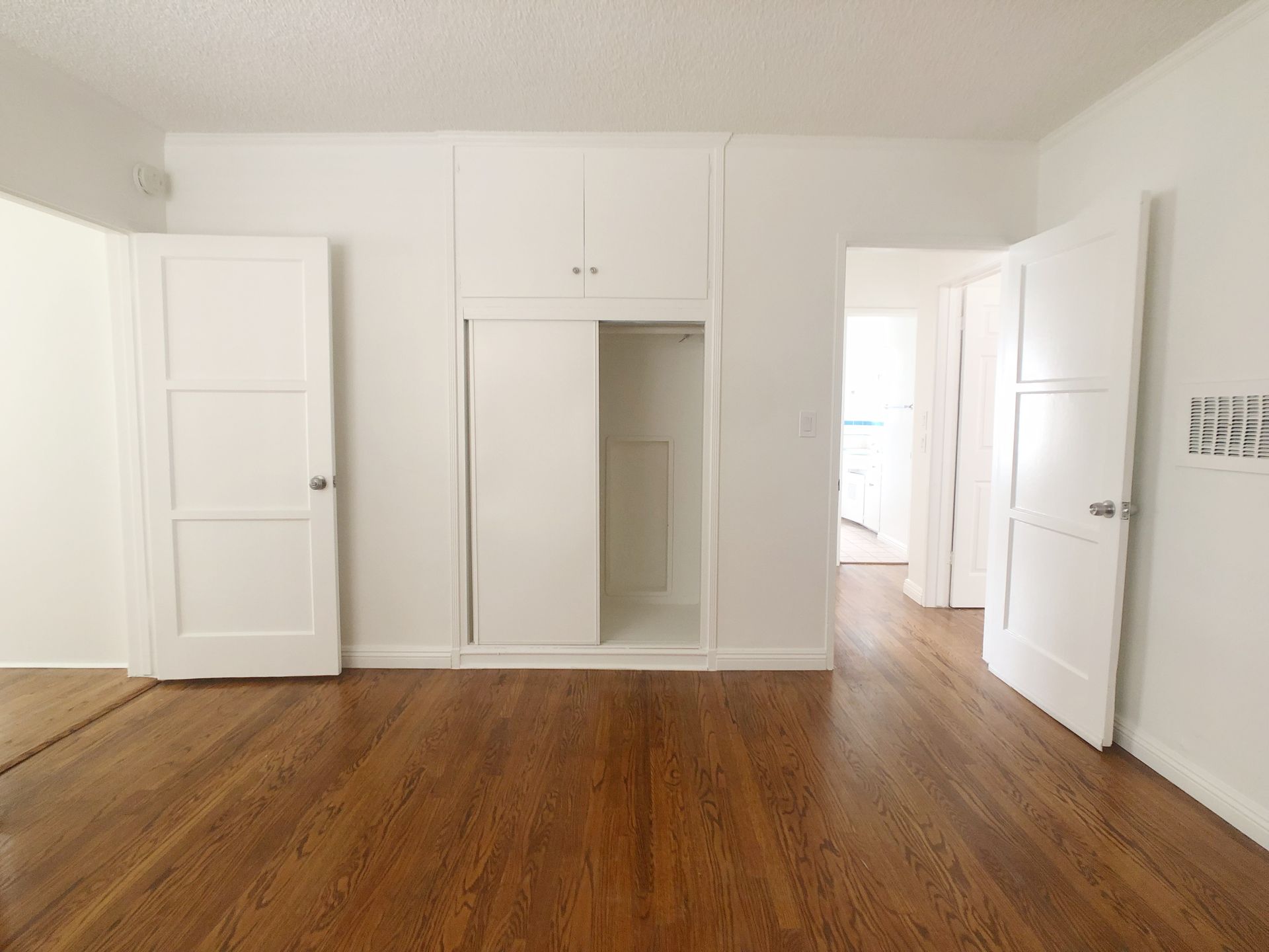 An empty room with hardwood floors and white walls