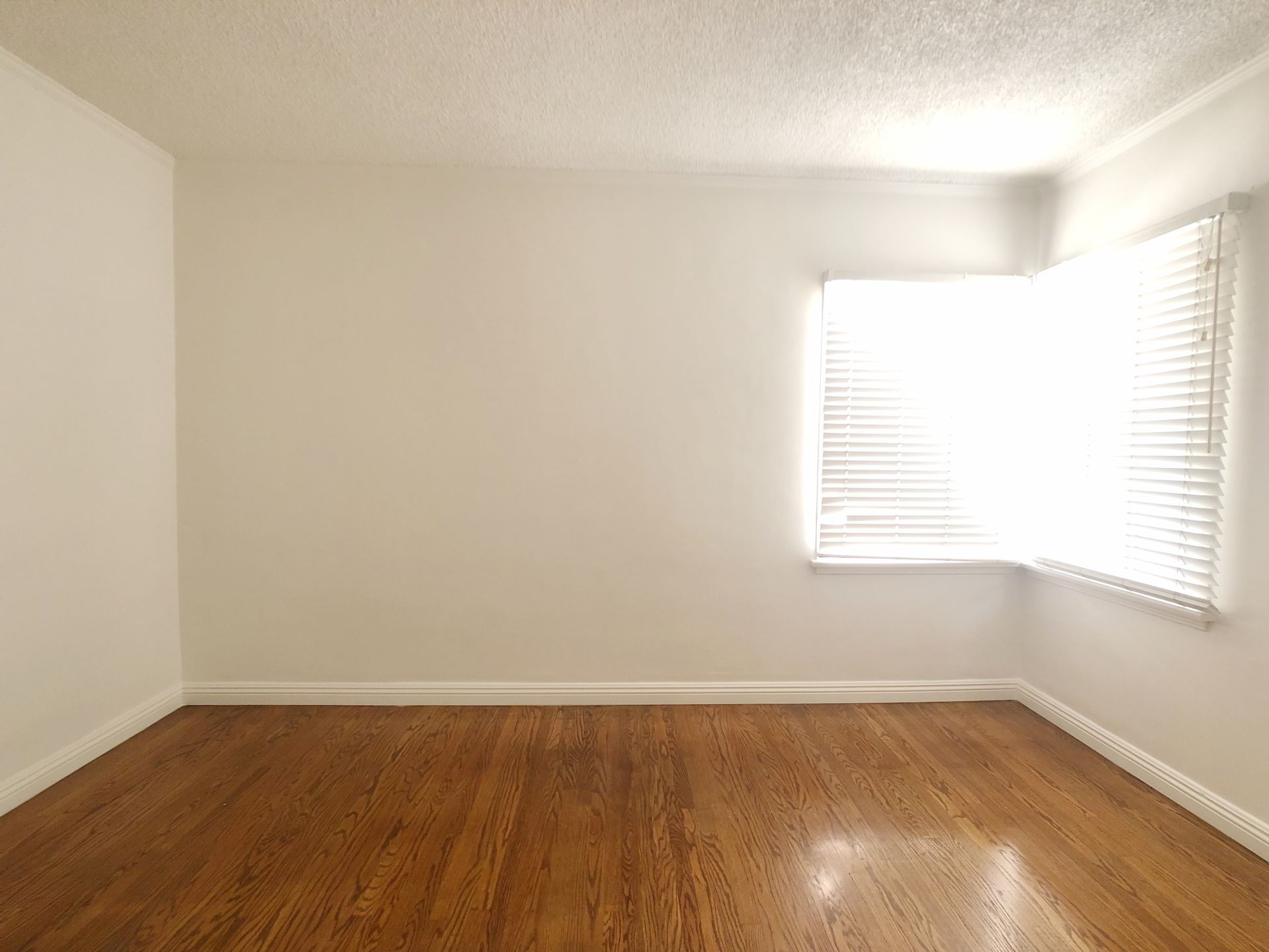 An empty room with hardwood floors and a window.