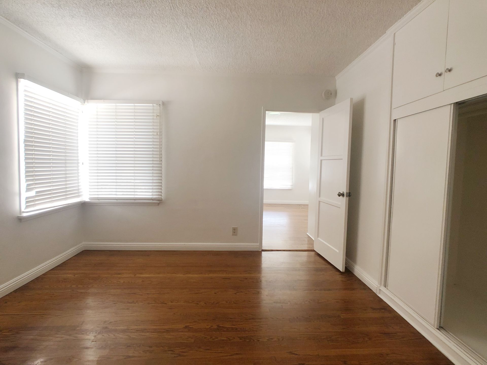 An empty room with hardwood floors and white walls