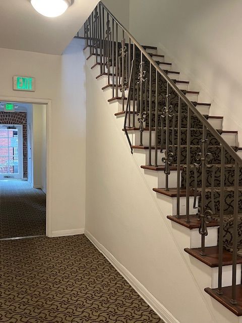 A hallway with stairs and a green exit sign