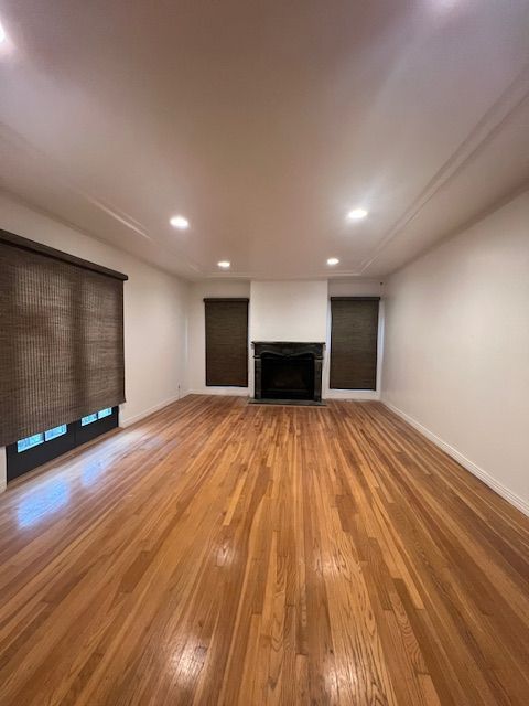 An empty living room with hardwood floors and a fireplace.