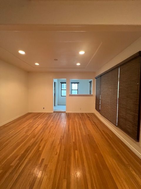 An empty living room with hardwood floors and white walls
