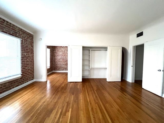 An empty room with hardwood floors and a brick wall