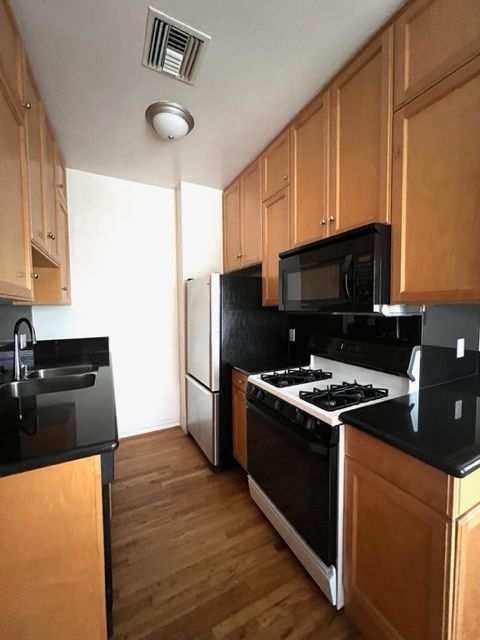 A kitchen with wooden cabinets and black counter tops