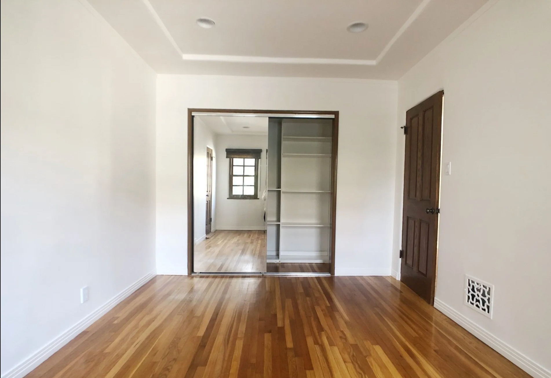 An empty room with hardwood floors and white walls