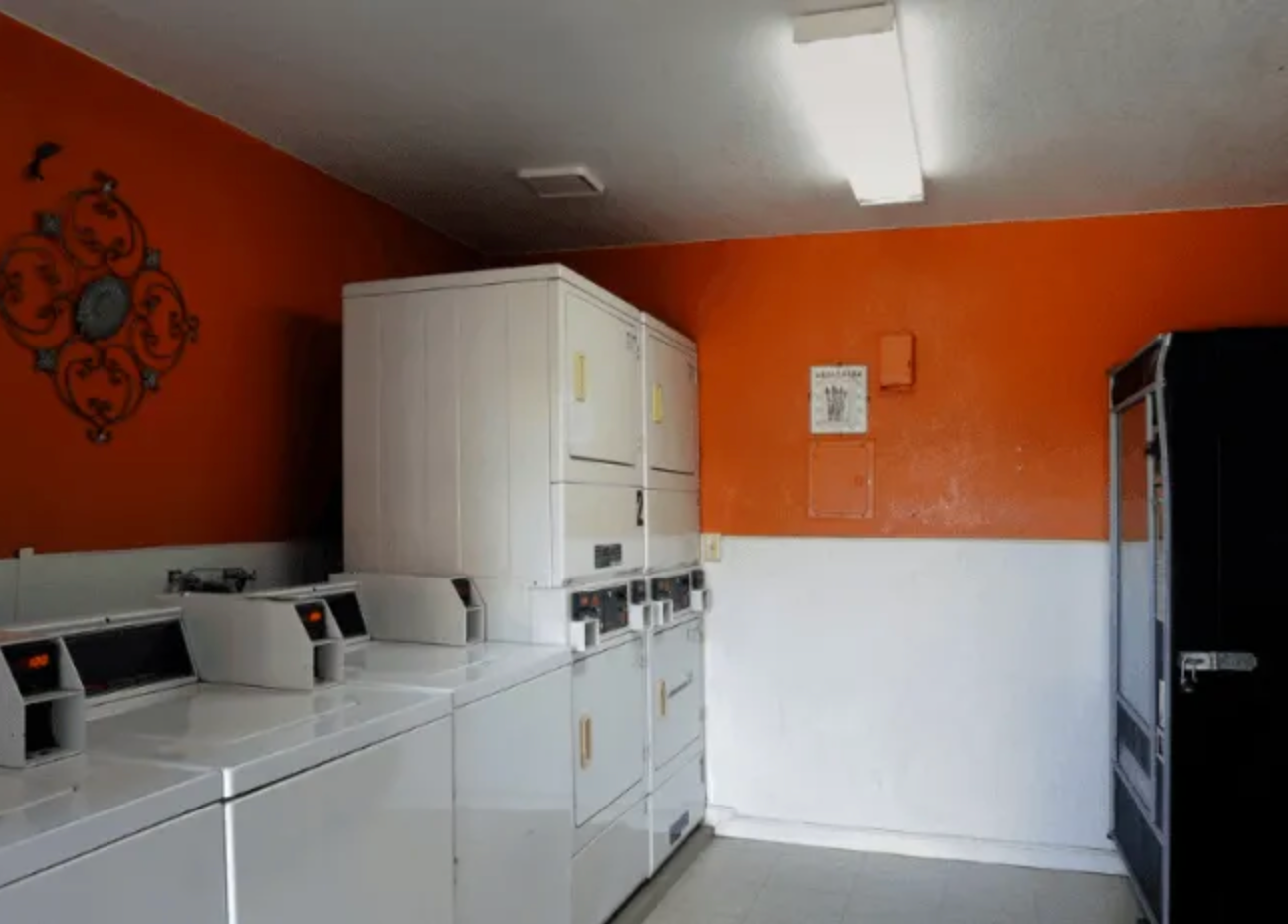 A laundromat with orange walls and white appliances