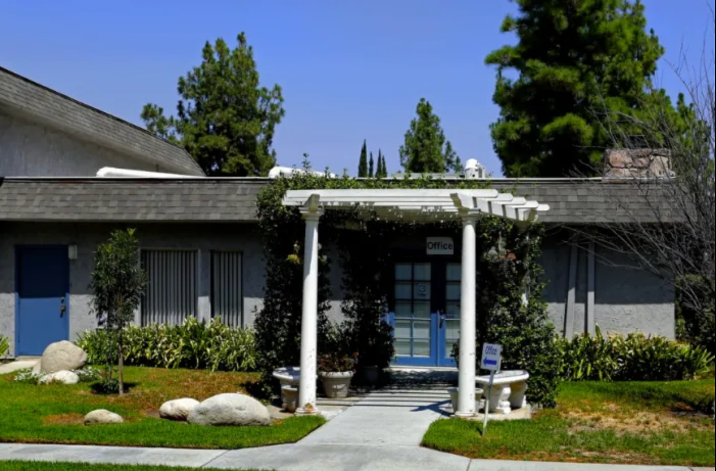 A house with a white pergola and a blue door