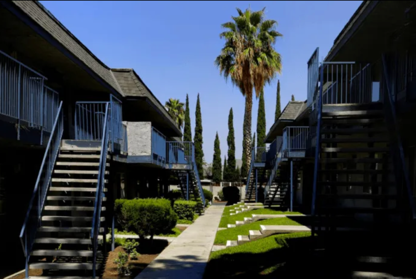 A row of apartment buildings with palm trees and stairs
