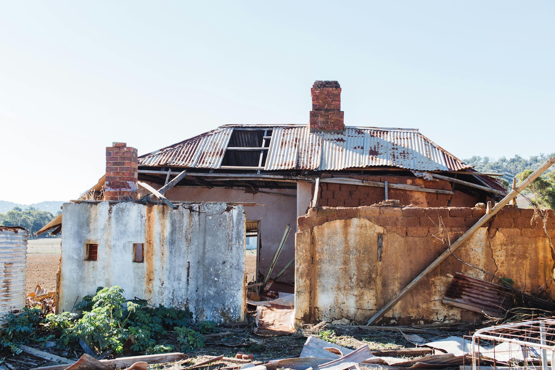 Ruined building with rusted roof and chimneys; daylight scene.