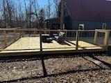 A wooden deck with chairs and a fence in front of a house.