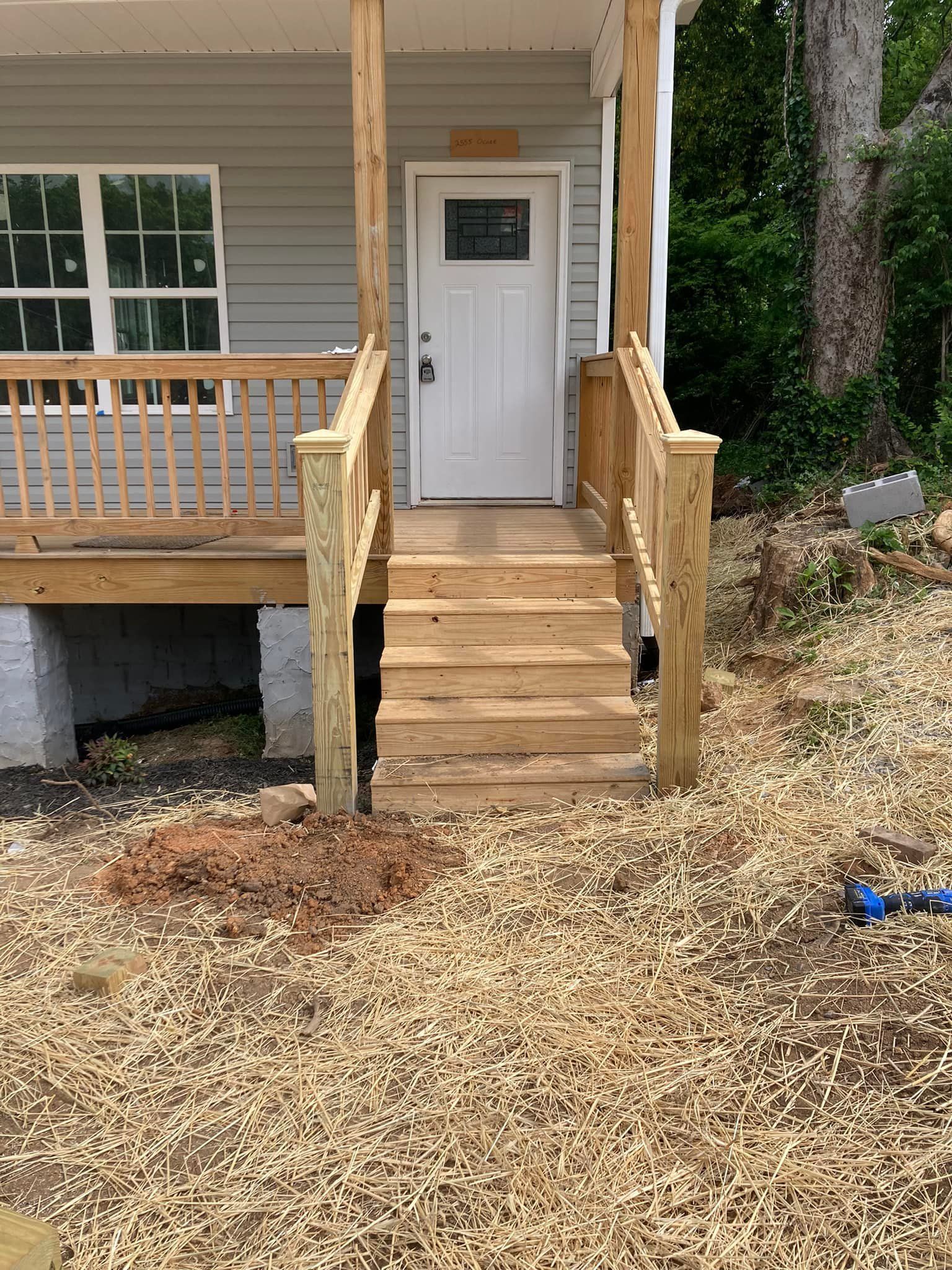A wooden porch with stairs leading up to the front door of a house.