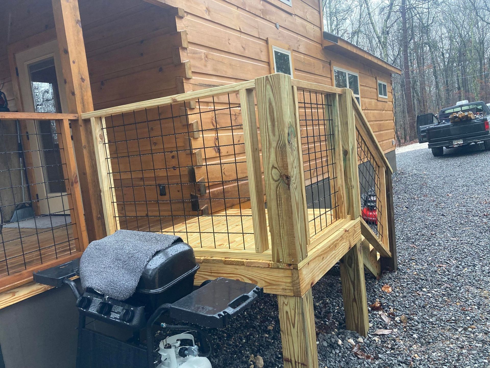 A wooden deck with stairs leading up to a log cabin.
