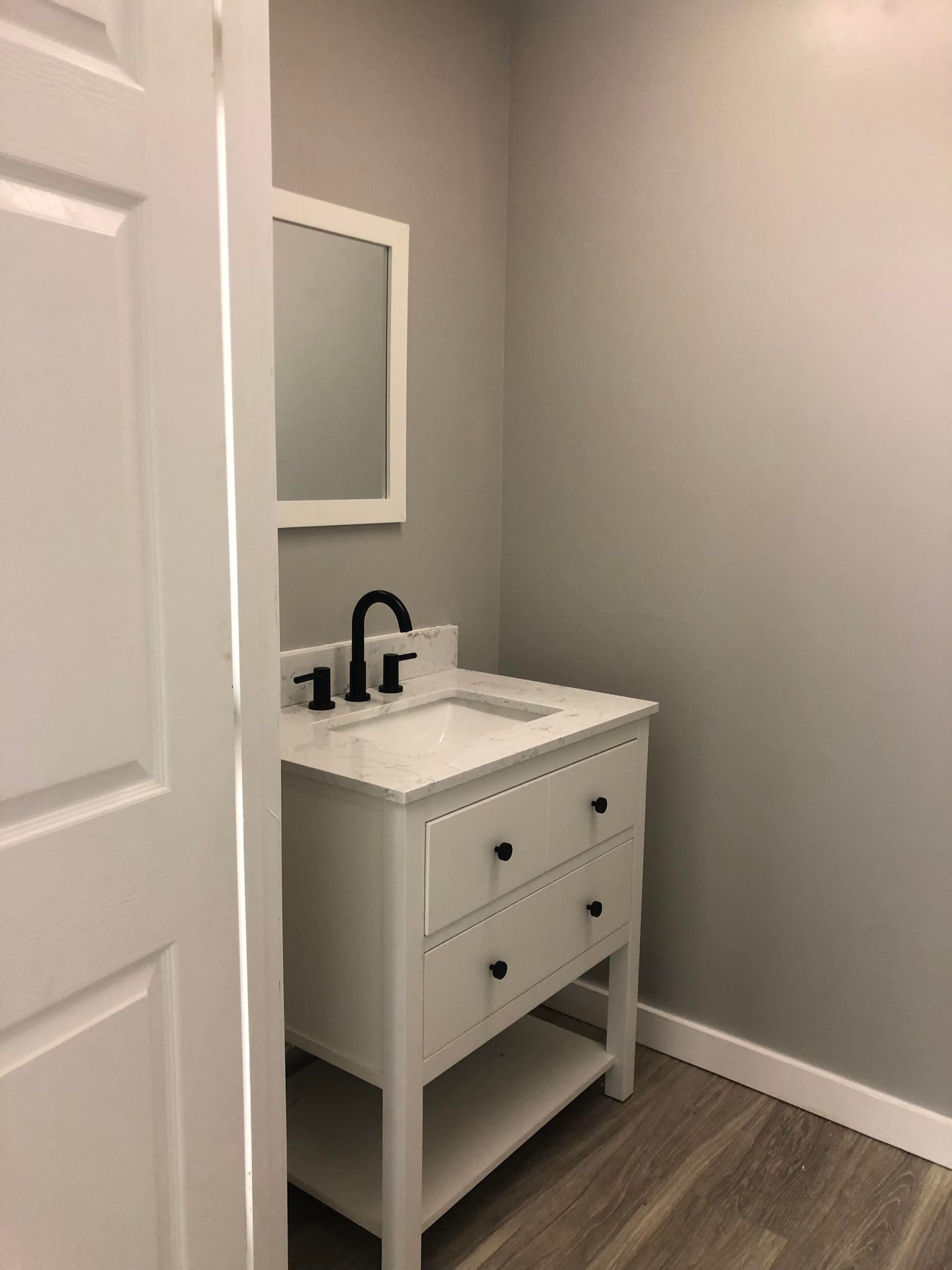 A bathroom with a white vanity and a mirror.