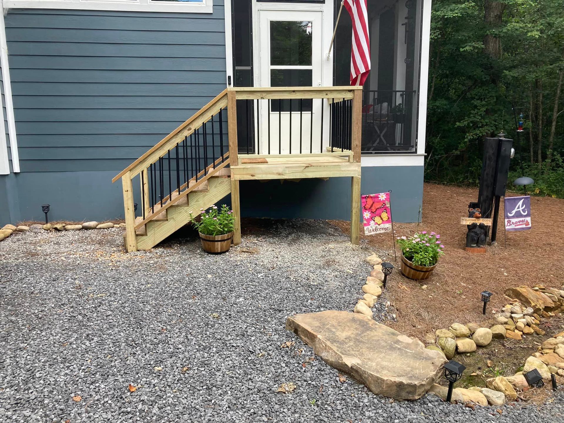 A blue house with a screened in porch and stairs.
