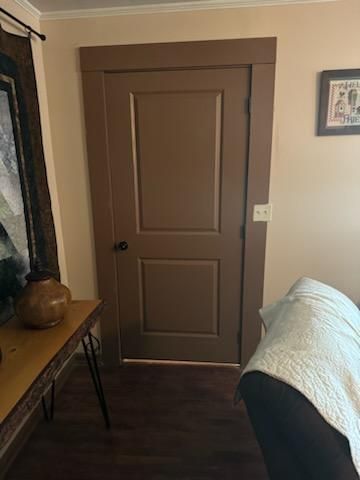 A living room with a brown door , a couch , a table and a picture on the wall.