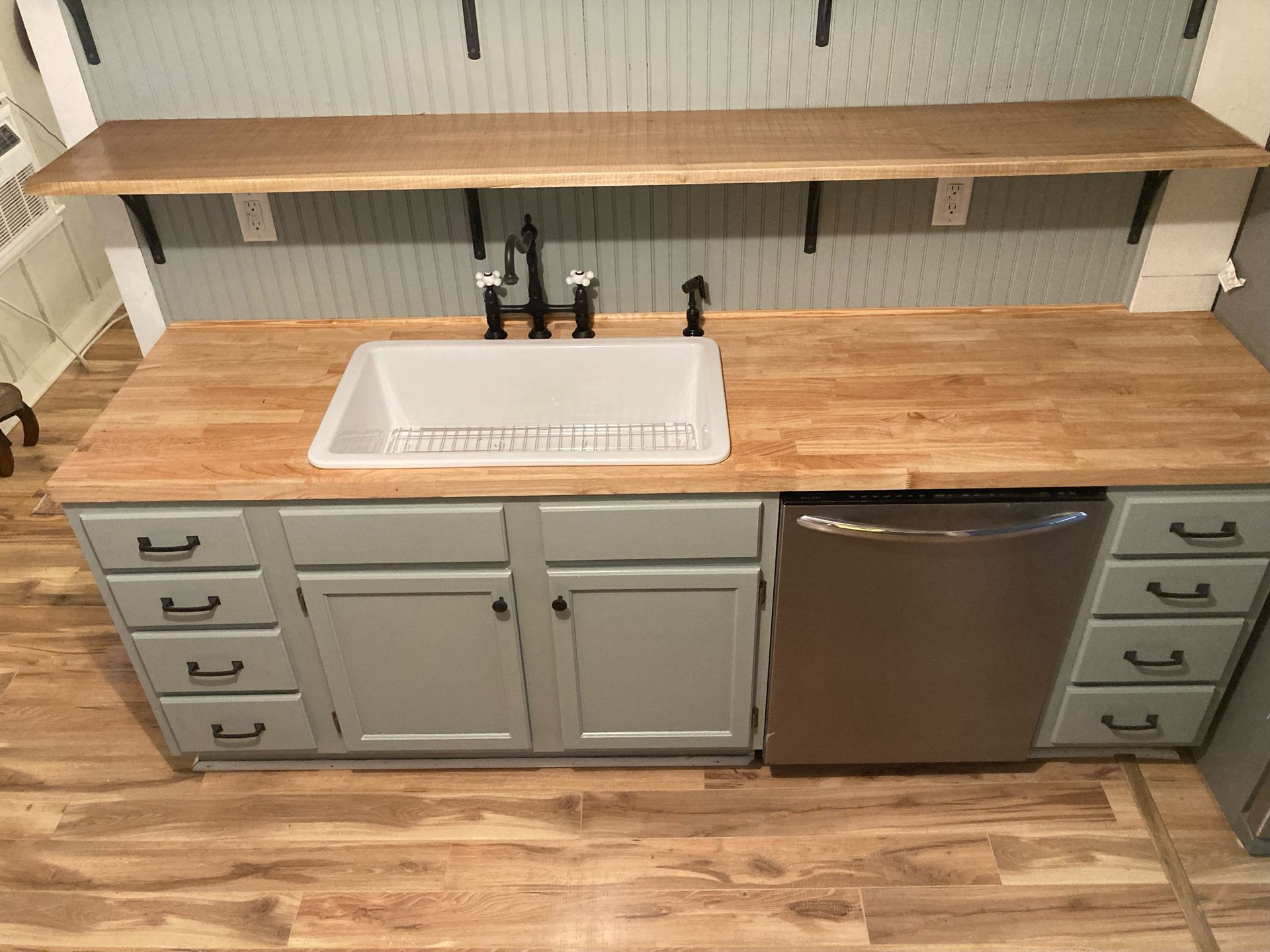 A kitchen with a sink , dishwasher , and wooden counter tops.