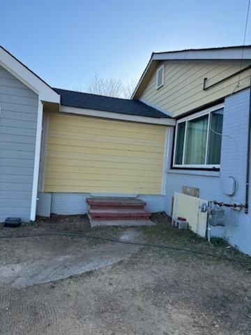 The back of a house with a yellow siding and a blue wall.