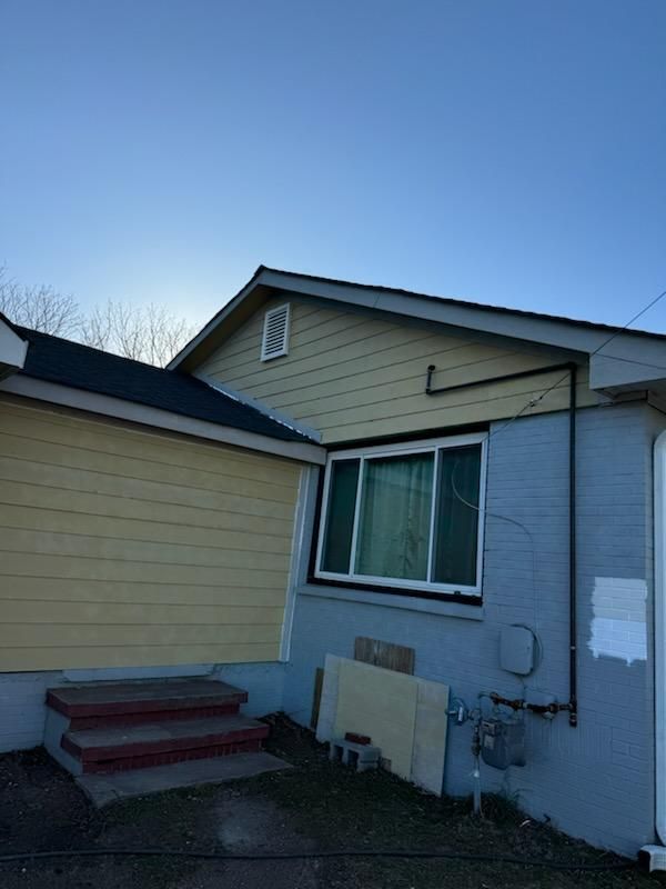 A small house with a blue roof and yellow siding