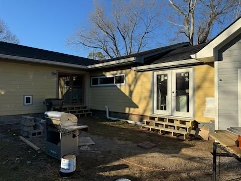 A yellow house with a grill in the backyard.