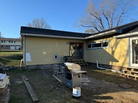 A yellow house with a grill in the backyard.