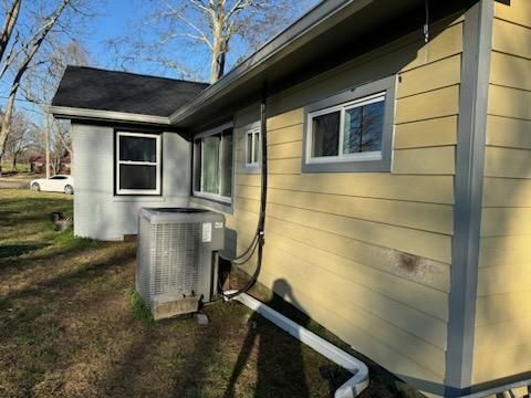 A yellow house with a black roof and a white car parked in front of it.