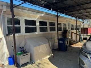 A car is parked under a canopy in front of a mobile home.