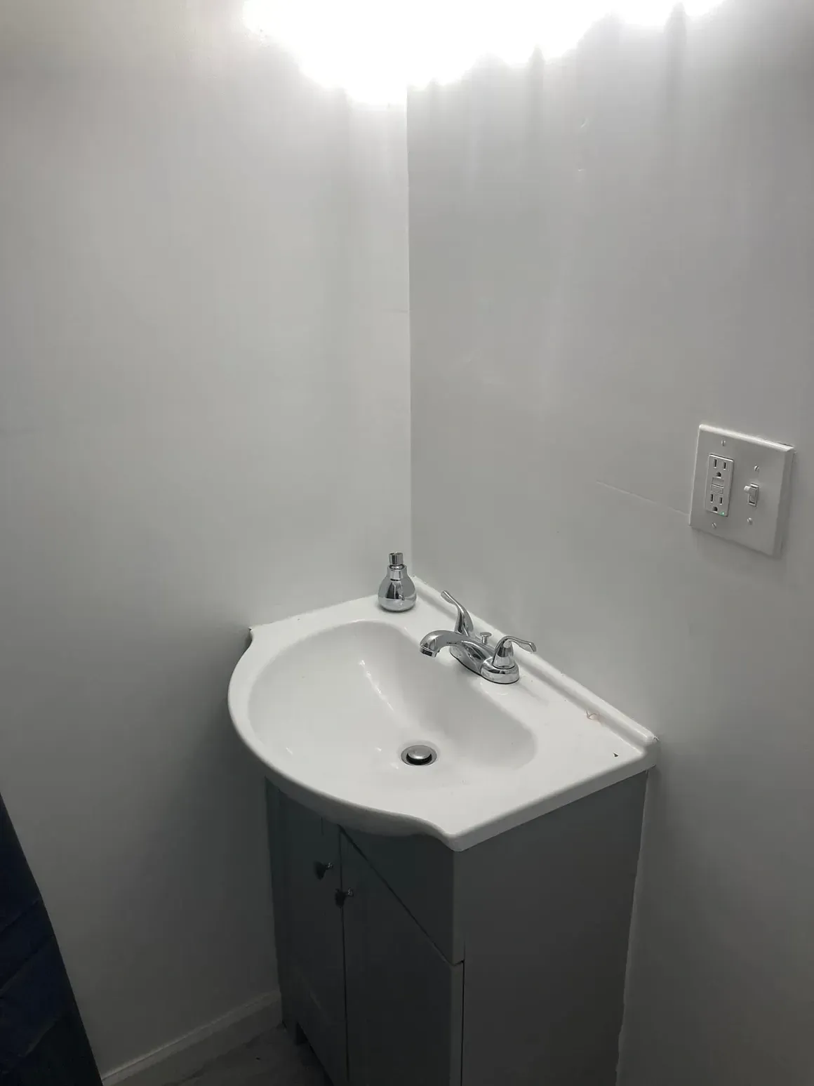 A bathroom with a sink and a light on the wall.
