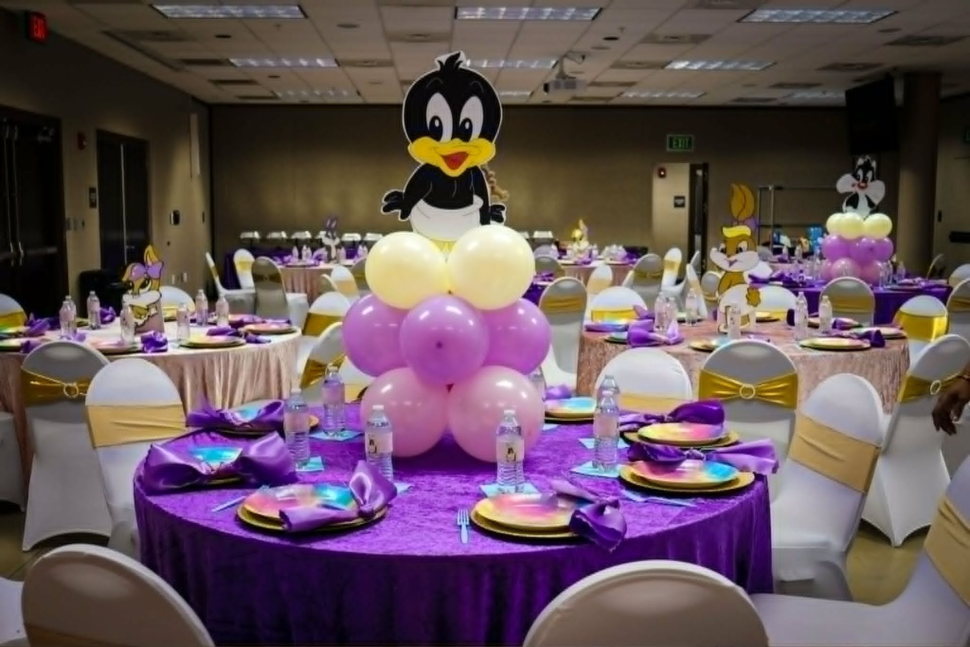 Banquet hall with purple table settings and a large black-and-white cartoon balloon centerpiece.