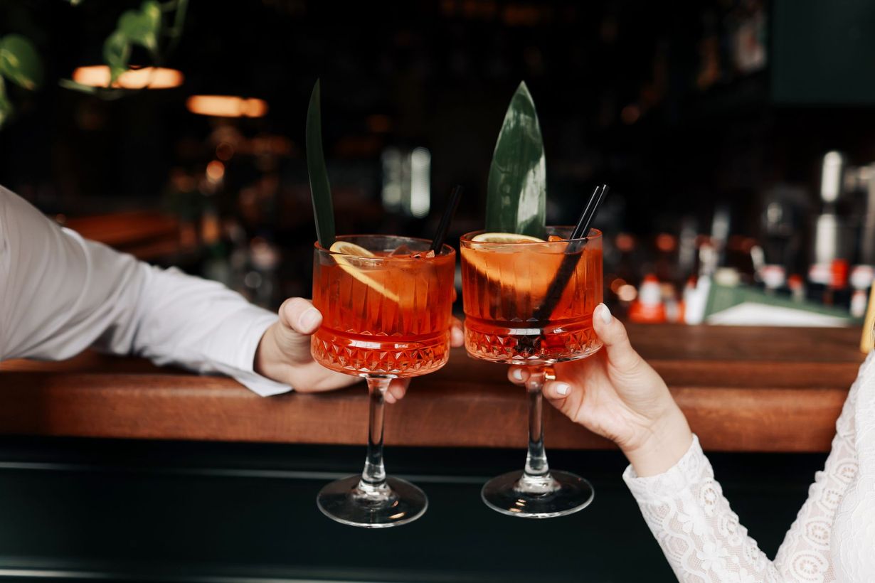 un uomo e una donna tengono in mano due bicchieri di cocktail .