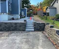 Backyard retaining wall with central concrete steps and an orange cone at the top