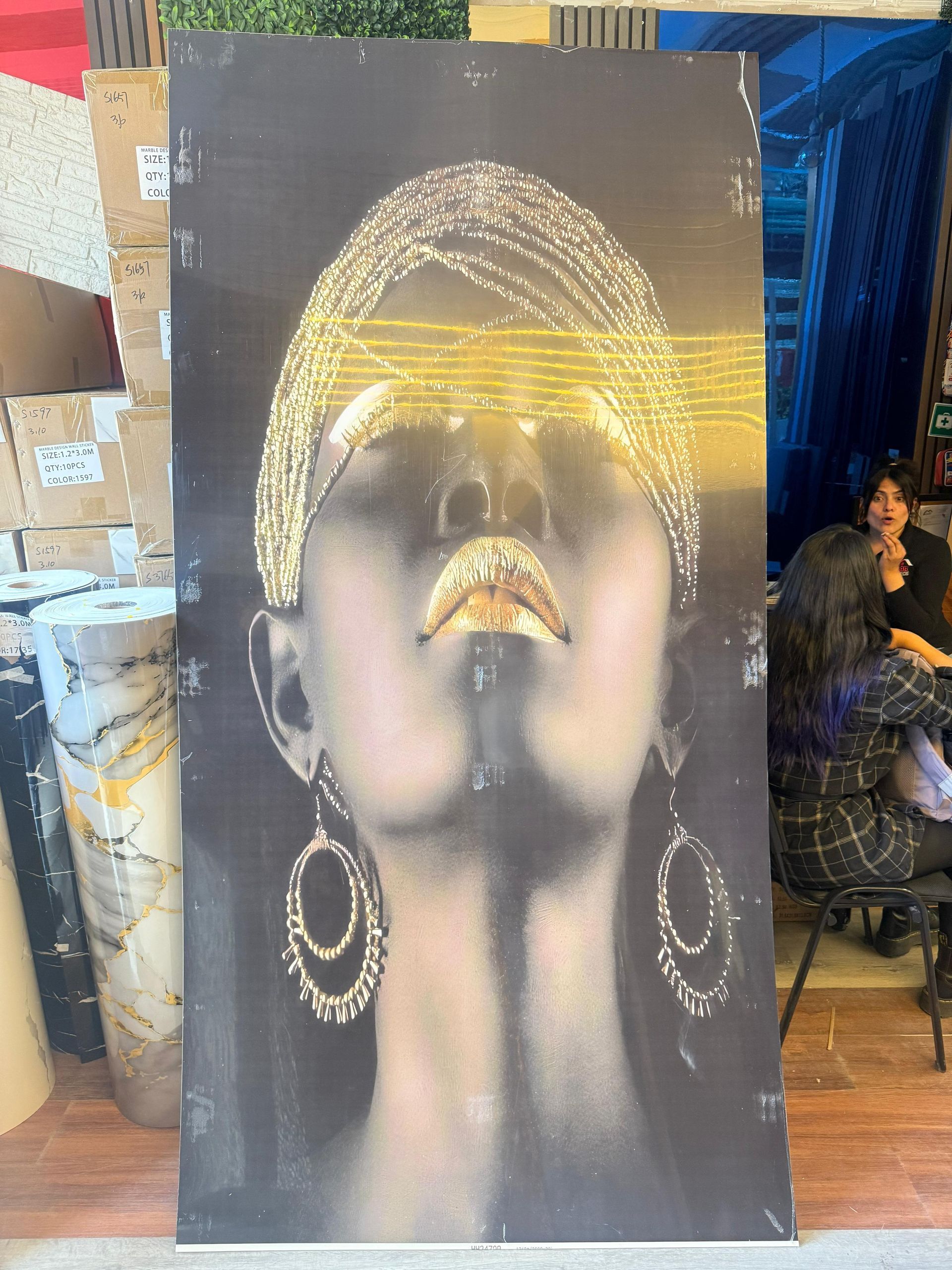 Mujer con adornos dorados, fondo oscuro. Ojos cubiertos, boca abierta, pendientes, tocado, raya amarilla en la cara.