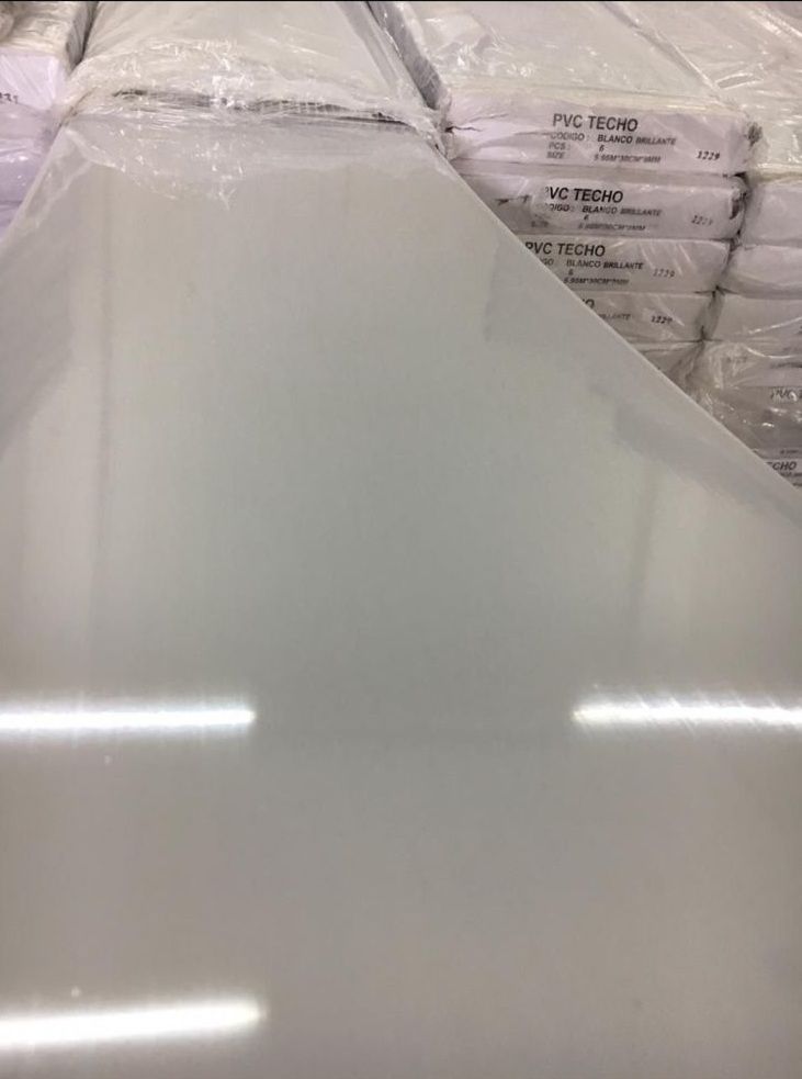 Pila de láminas de PVC blancas opacas, envueltas en plástico transparente.