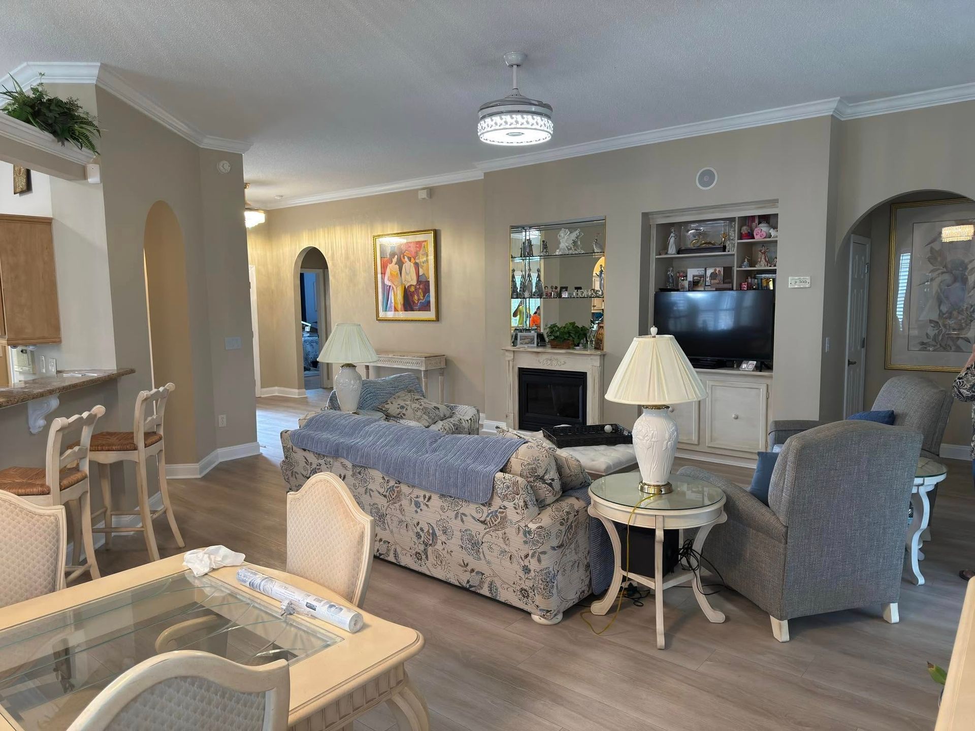 Open living room with beige walls, floral sofa, and gray armchair.