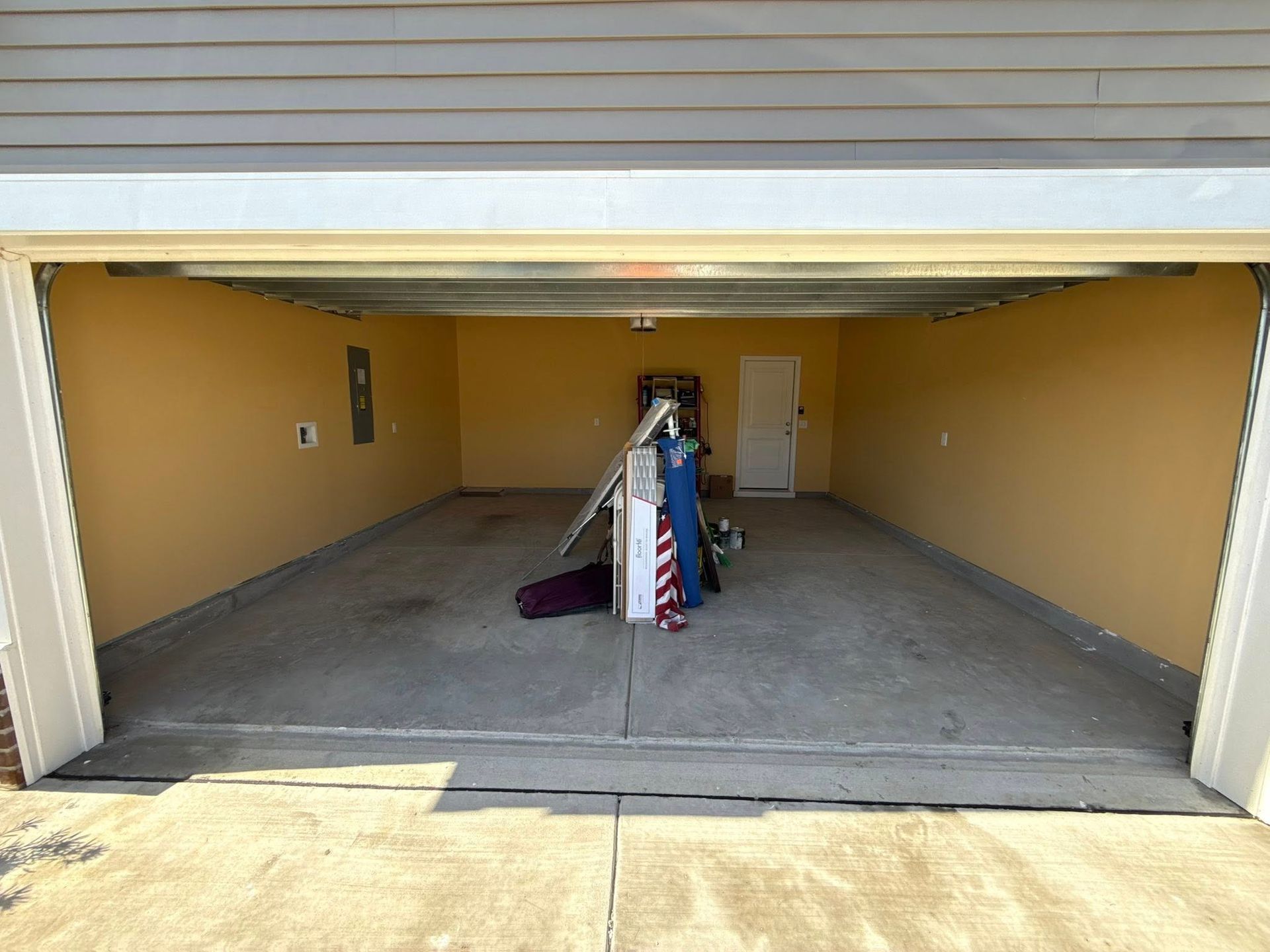 Garage interior with tan walls, concrete floor, and a small amount of clutter.