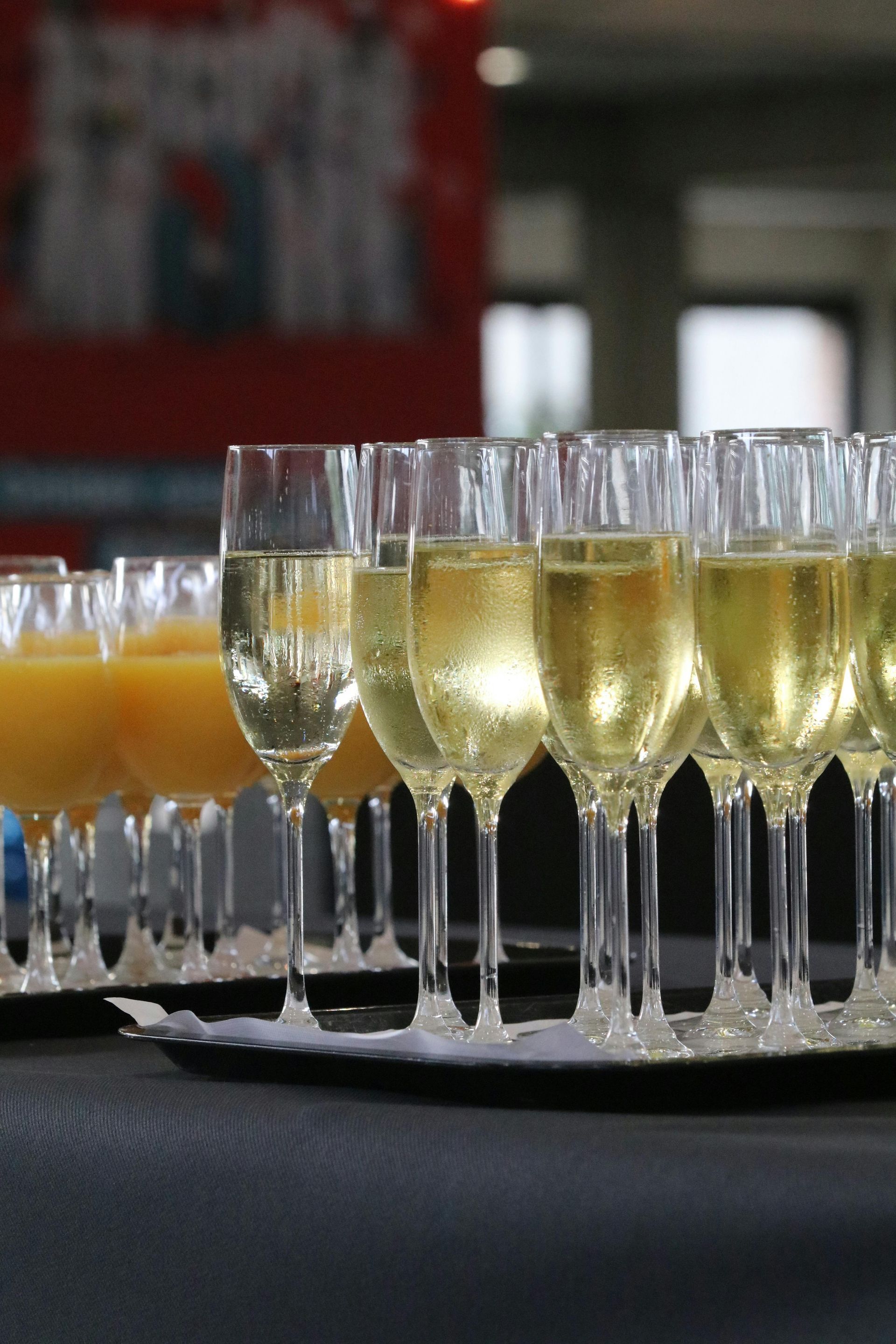 Champagne flutes and orange juice glasses on a tray, ready for a corporate event in Sydney.