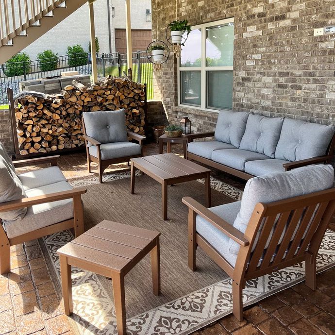A patio with a couch , chairs , tables and a rug.