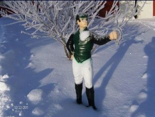 A figurine of a man in a green vest is standing in the snow